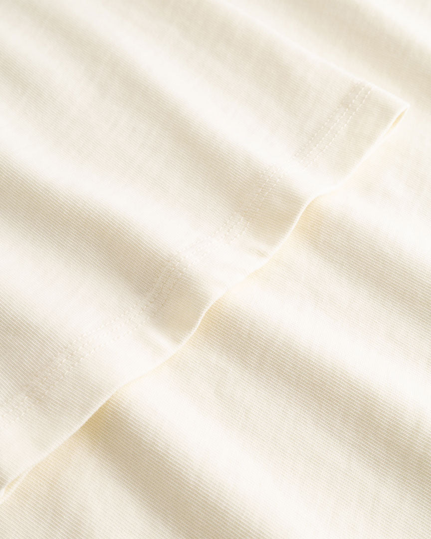 Closeup view of arm stitchings on cream colored T-shirt