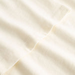 Closeup view of arm stitchings on cream colored T-shirt