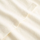 Closeup view of arm stitchings on cream colored T-shirt