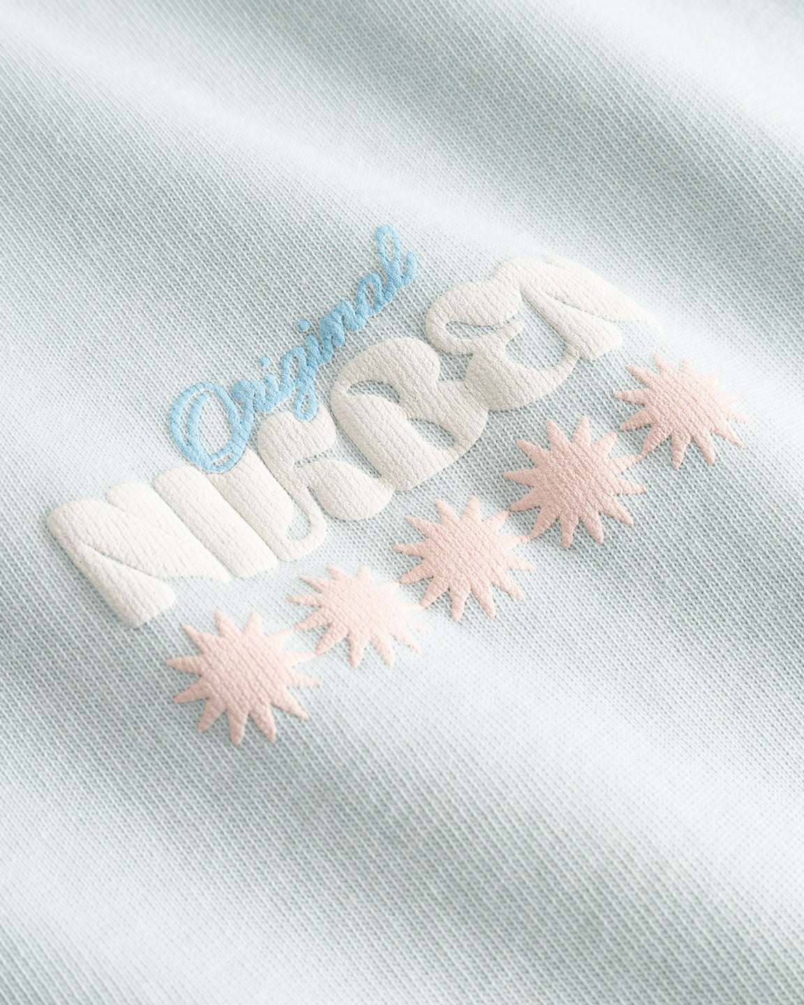 Closeup view of multicolored Nikben logo on pale blue T-shirt
