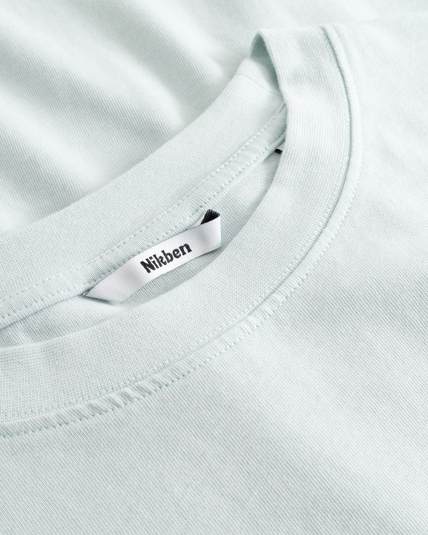 Closeup view of Nikben necklabel on pale blue T-shirt