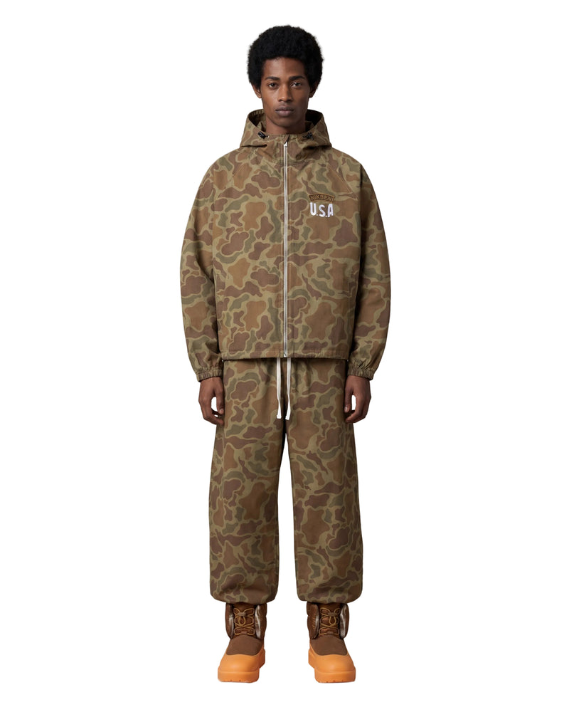 A model stands against a light gray background wearing a matching camouflage hooded jacket and sweatpants set, with brown and orange work boots. The jacket has a white 'USA' logo on the chest.