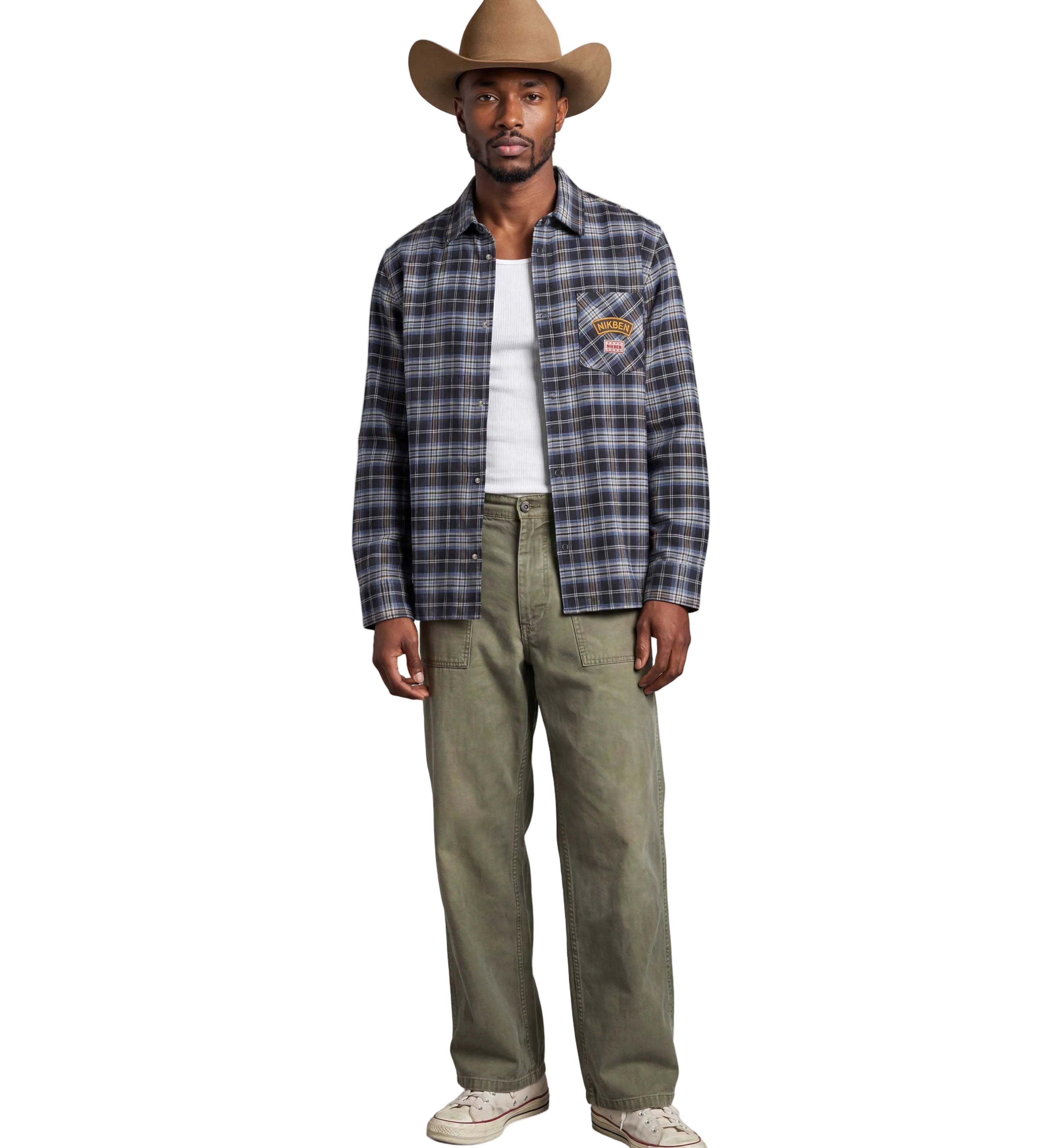 A man modeling a long-sleeve plaid button-up shirt in blue, gray, and black, worn open over a white t-shirt, paired with olive green pants and a tan cowboy hat, against a light gray background.
