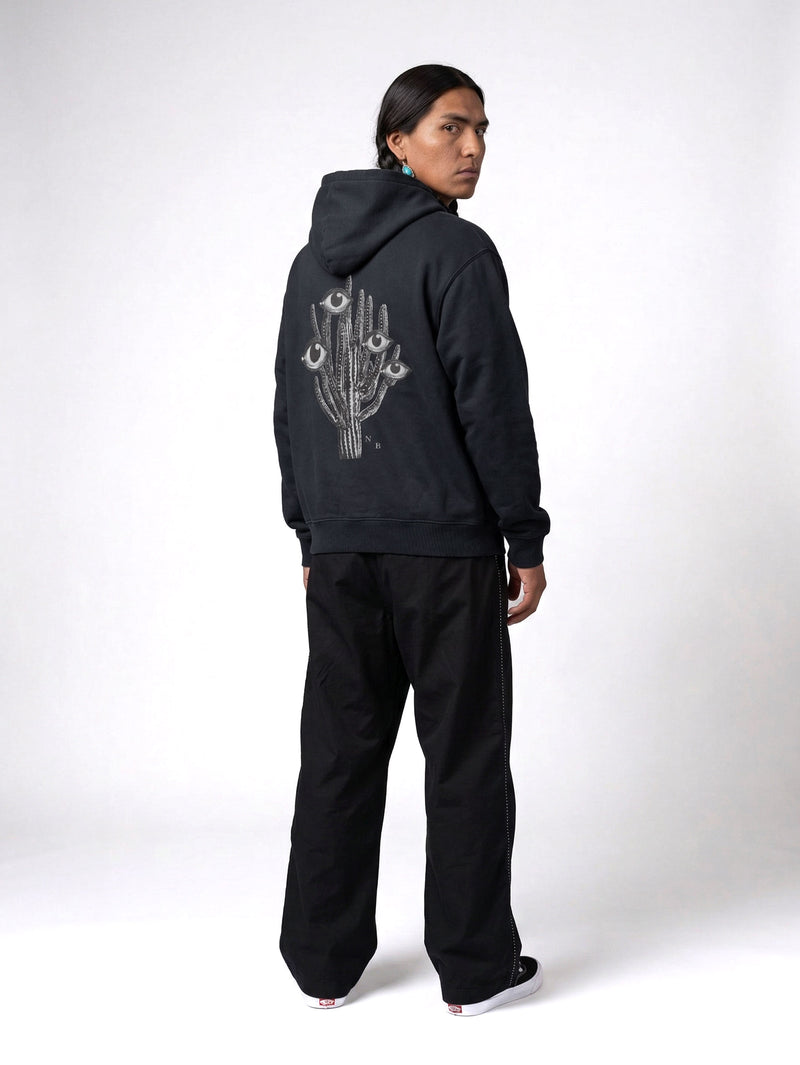 Back of male model wearing black hoodie with black and white cactus print on the back