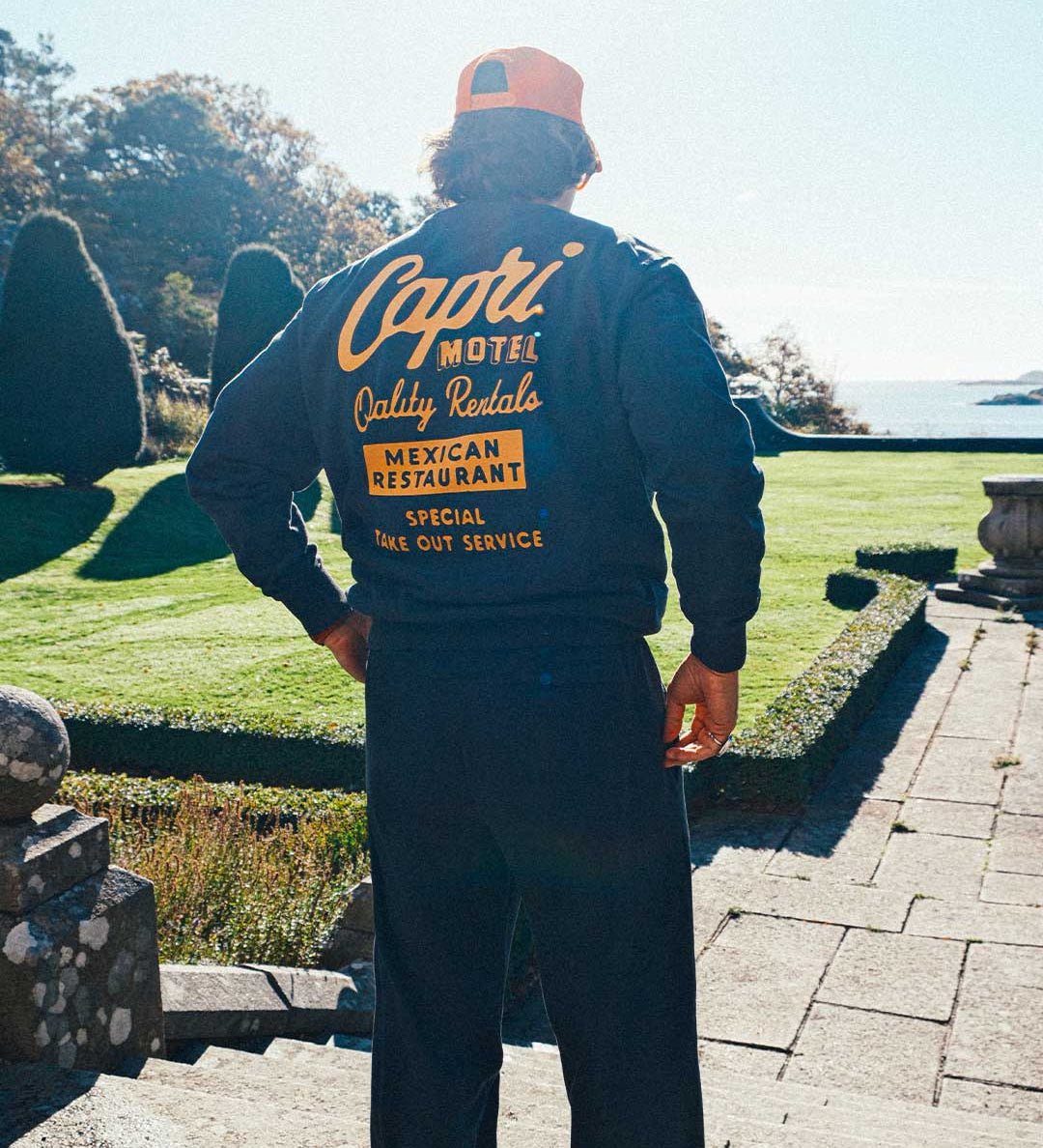 model wearing a full sweatsuit with 'Capri Motel' text on the back