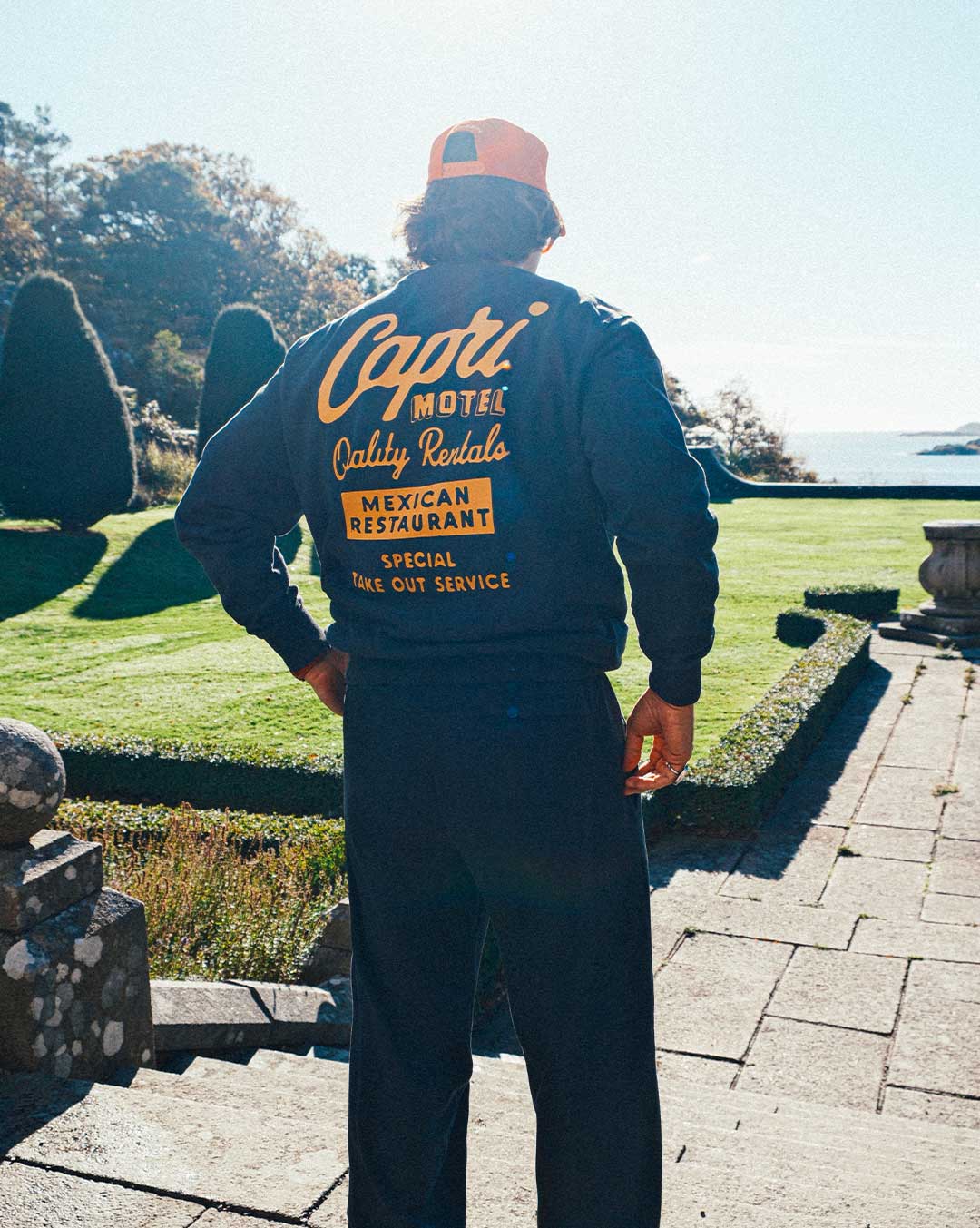 model wearing a full sweatsuit with 'Capri Motel' text on the back