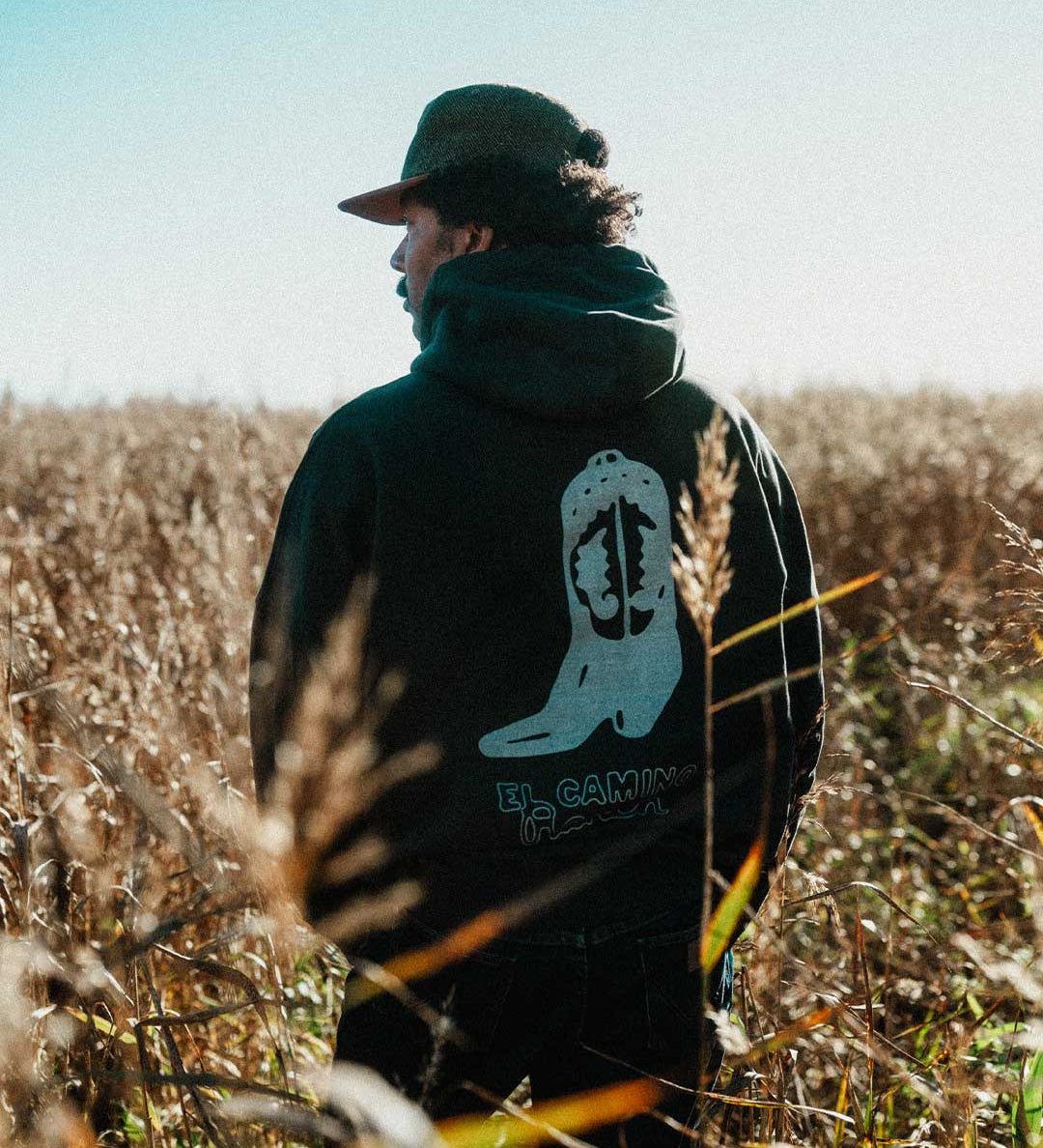 Model wearing a black hoodie with cowboy boot print on the back