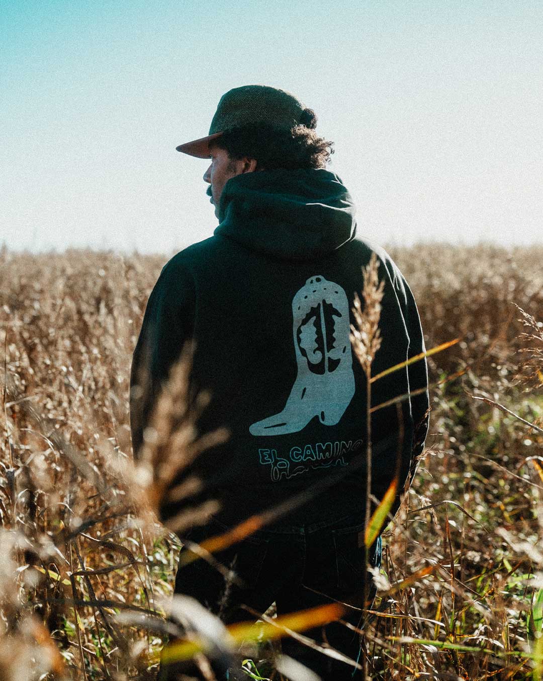 Model wearing a black hoodie with cowboy boot print on the back