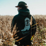 Model wearing a black hoodie with cowboy boot print on the back