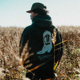 Model wearing a black hoodie with cowboy boot print on the back