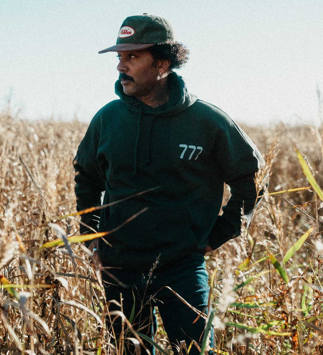 Model wearing a black hoodie with '777' logo on chest