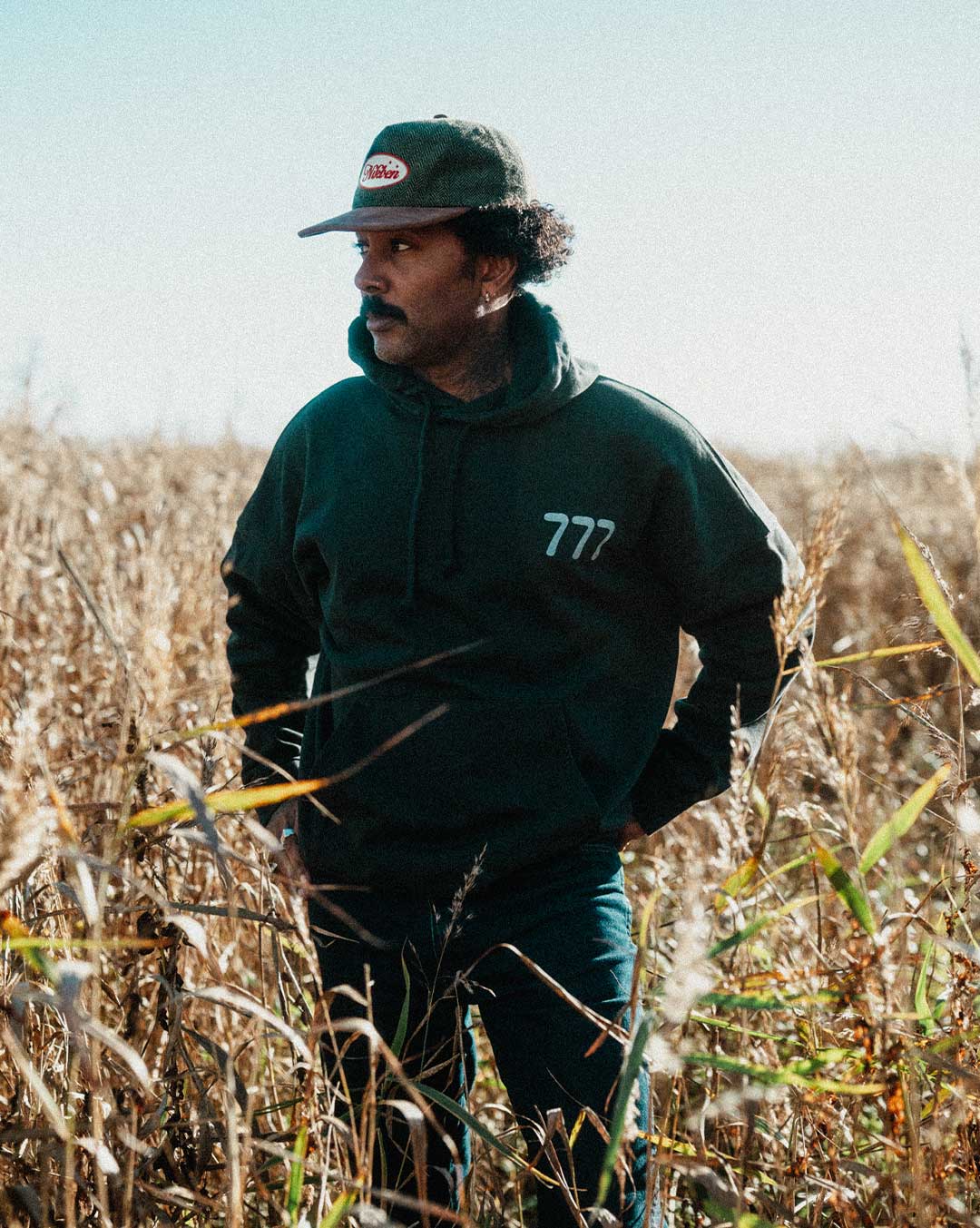 Model wearing a black hoodie with '777' logo on chest