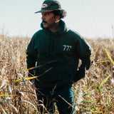 Model wearing a black hoodie with '777' logo on chest