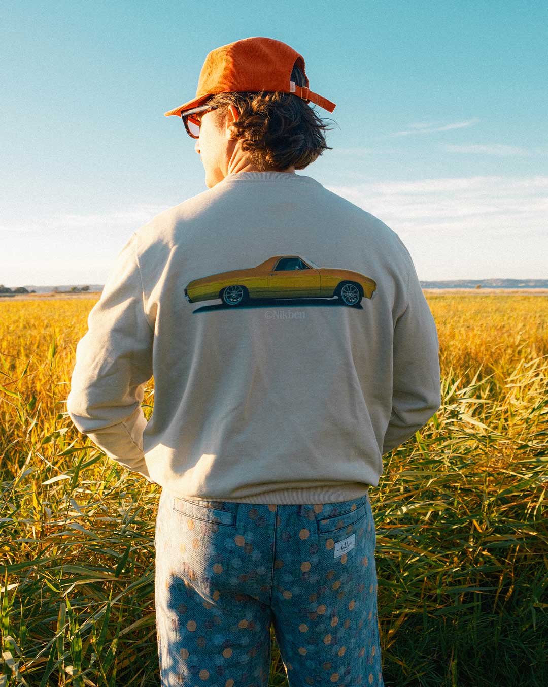 Model  wearing a beige sweatshirt with a vintage car design