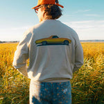 Model  wearing a beige sweatshirt with a vintage car design