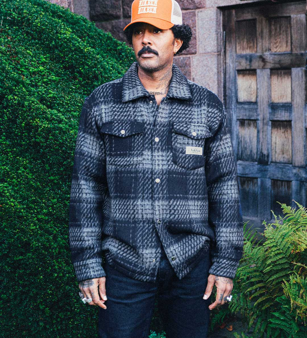 Model wearing navy grey checkered shirt with chest pockets.