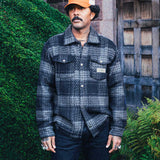 Model wearing navy grey checkered shirt with chest pockets.