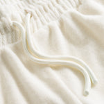 Close up on drawstring on off white low cut shorts in terry toweling fabric