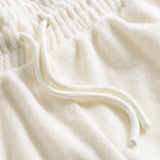Close up on drawstring on off white low cut shorts in terry toweling fabric