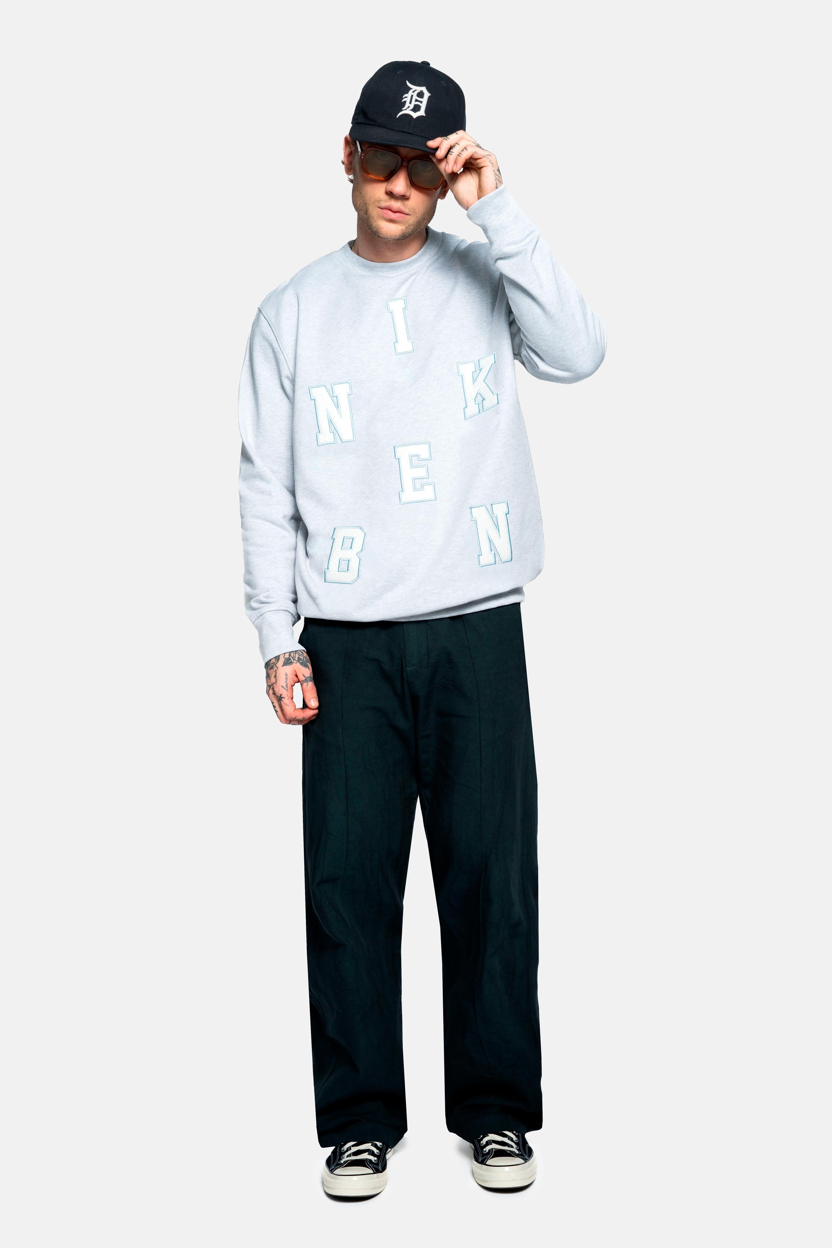 Male model wearing grey sweatshirt with embroidered Nikben letters