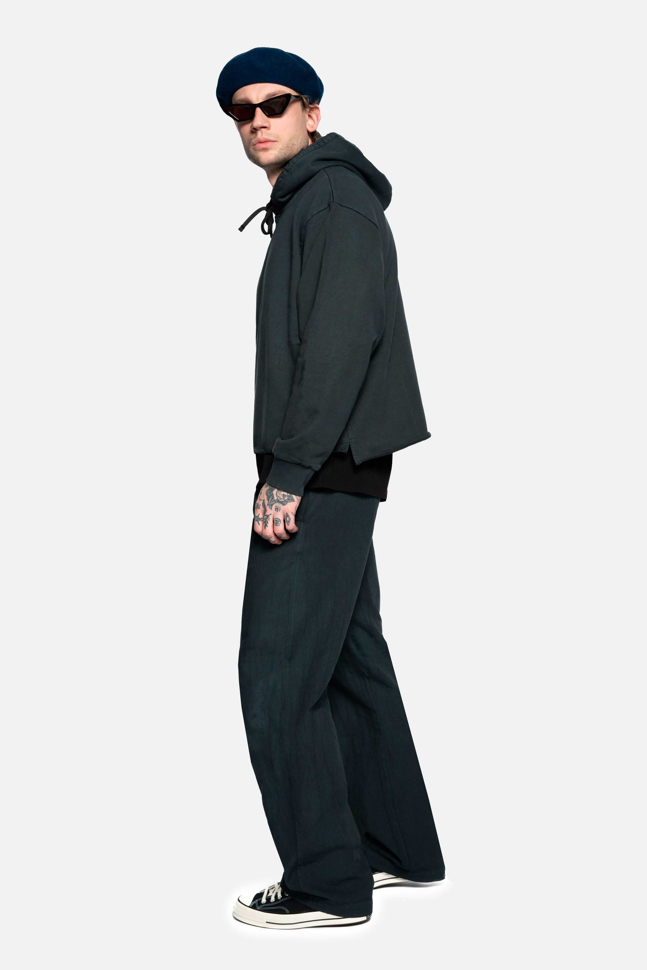 Male model wearing a black cropped hoodie with drawstrings and ribbed cuffs