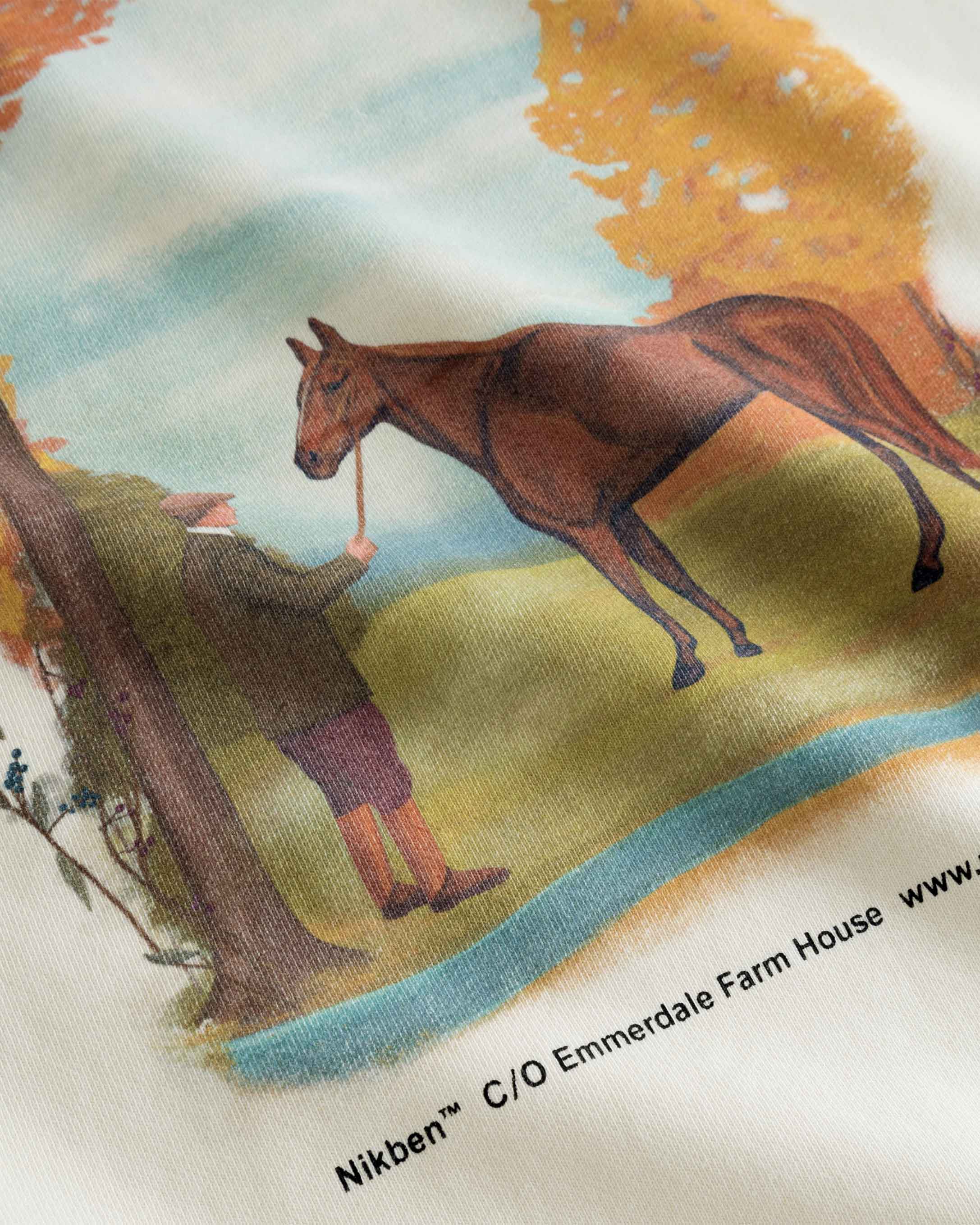 Close up of a man and horse print on a cream colored sweatshirt.