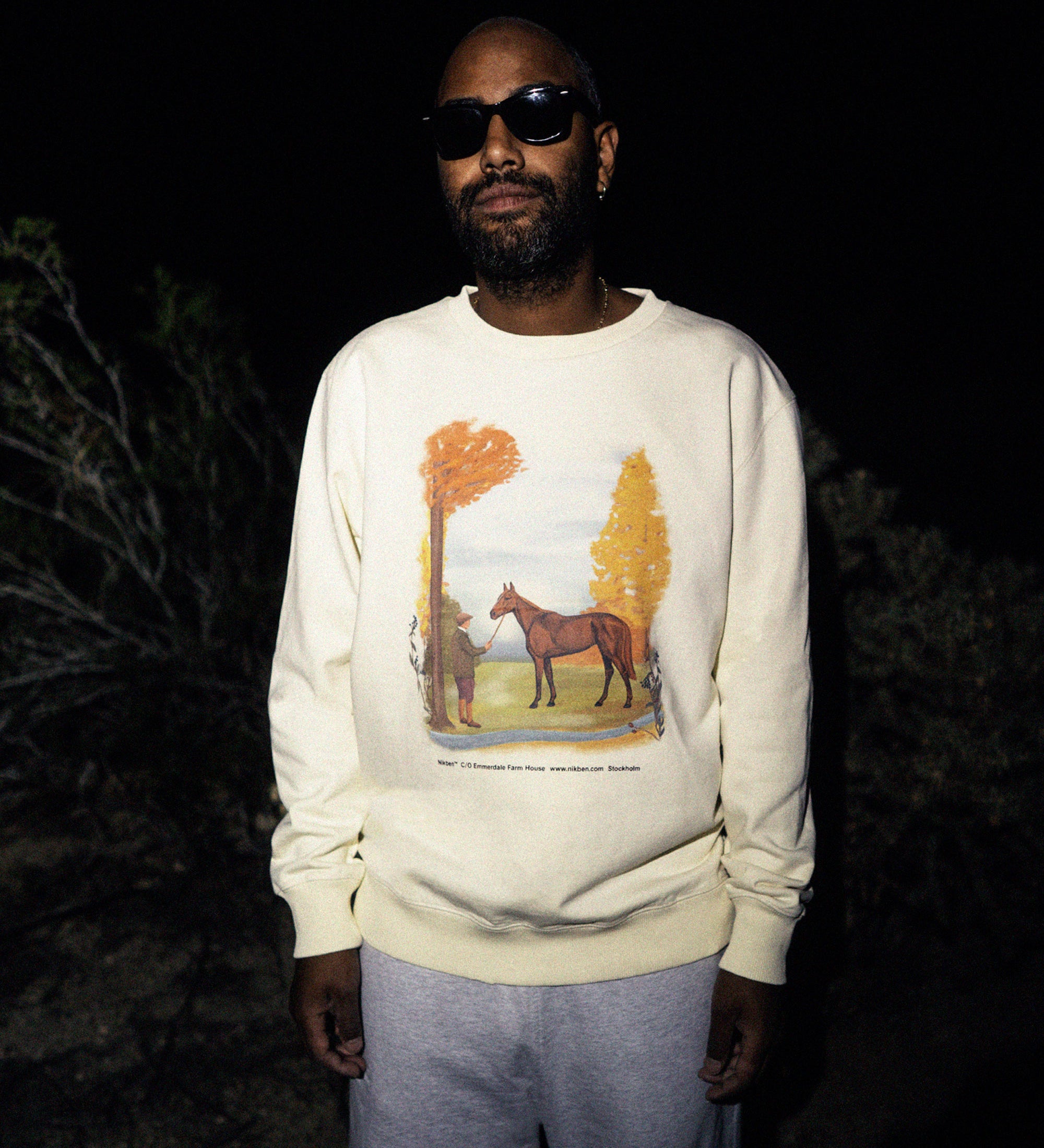 Male model wearing a cream colored sweatshirt with a man and a horse print.