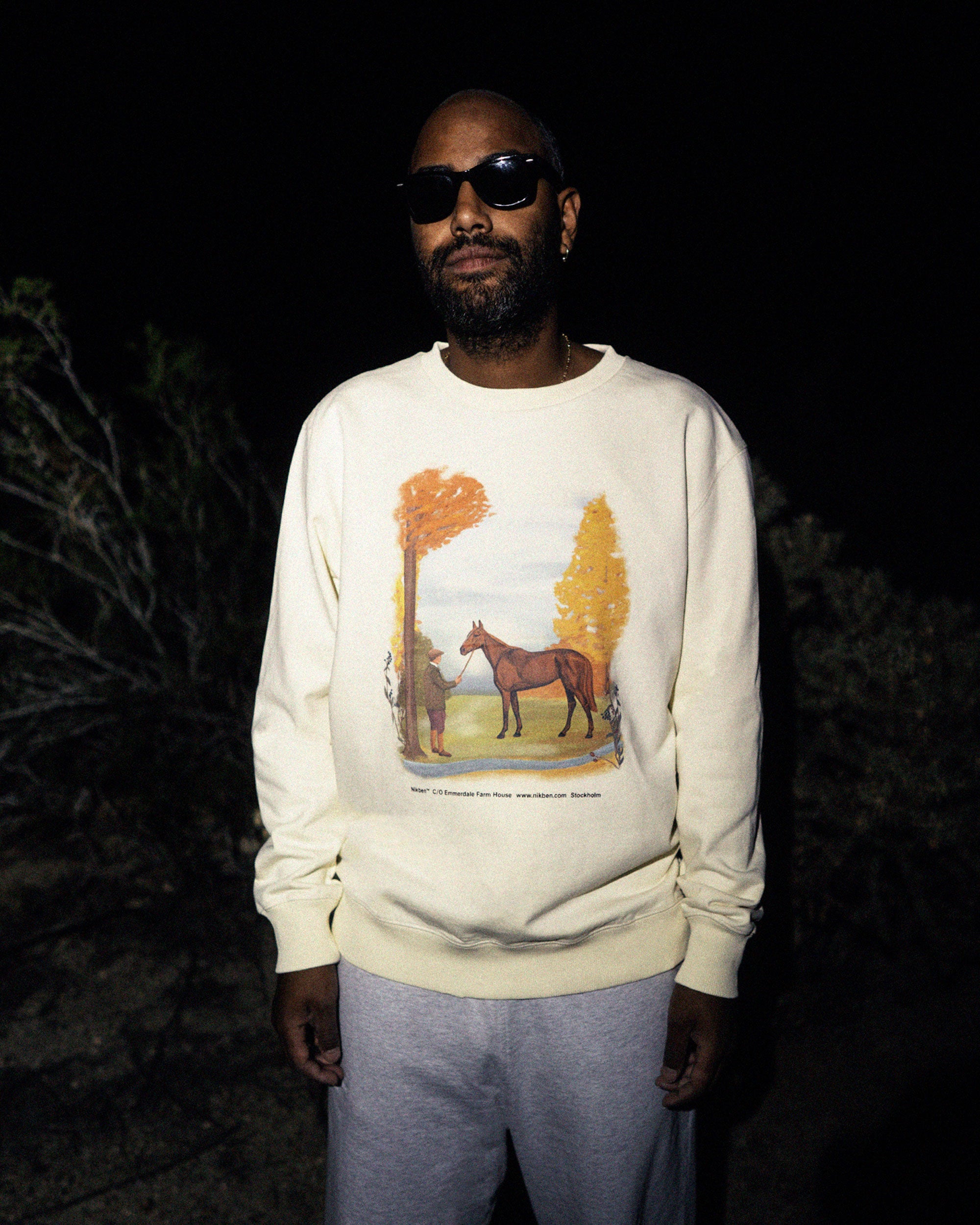 Male model wearing a cream colored sweatshirt with a man and a horse print.