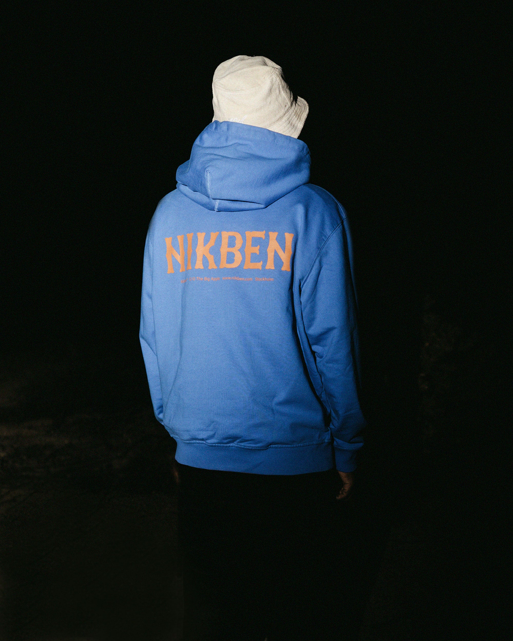 Back view of male model wearing blue unisex hoodie with orange 