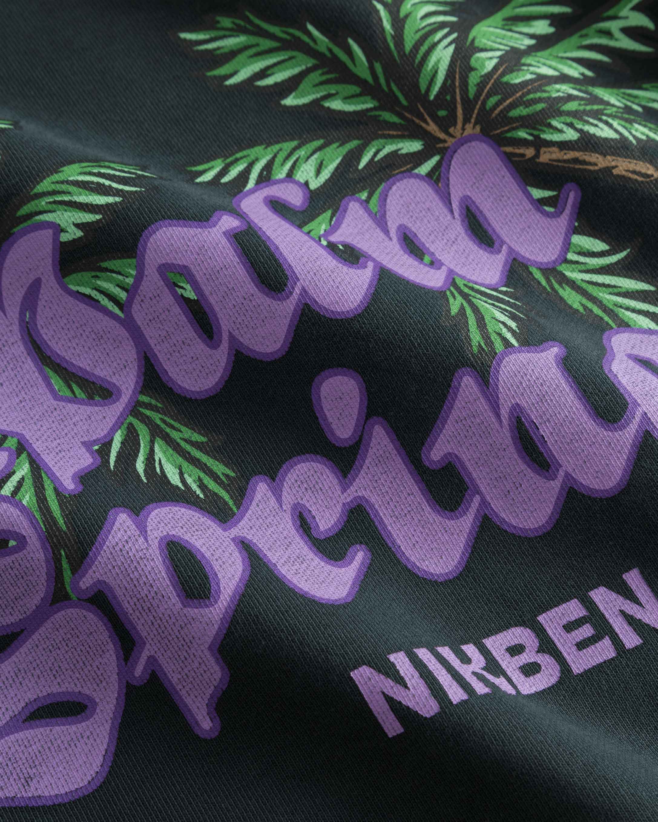 Close up view of purple and green print on washed black hoodie.