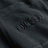 Close-up of chest pocket with tone in tone embroidered "nikben" logo on washed black T-shirt