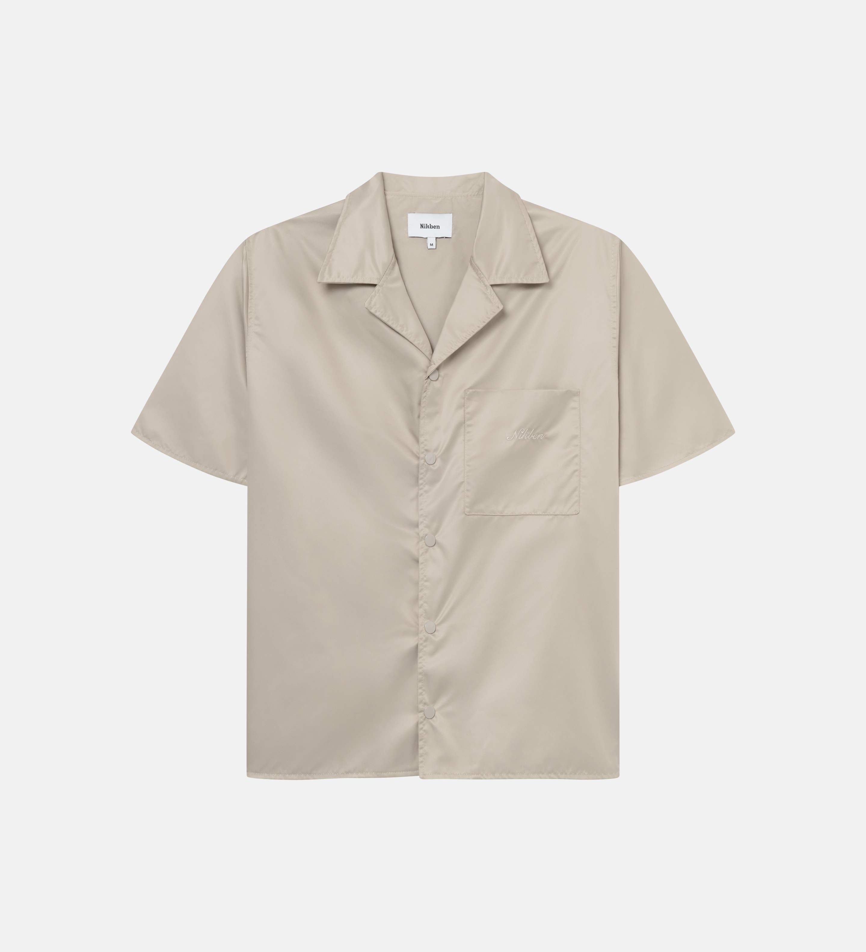 A beige short-sleeved shirt with snap button closure and embroidered Nikben logo on the breast pocket