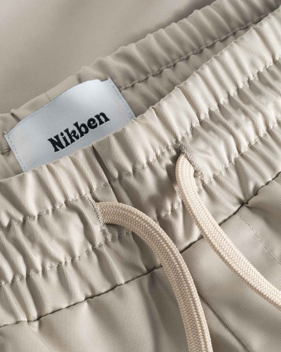 Close up of waistband and drawstrings on a pair of beige polyester shorts