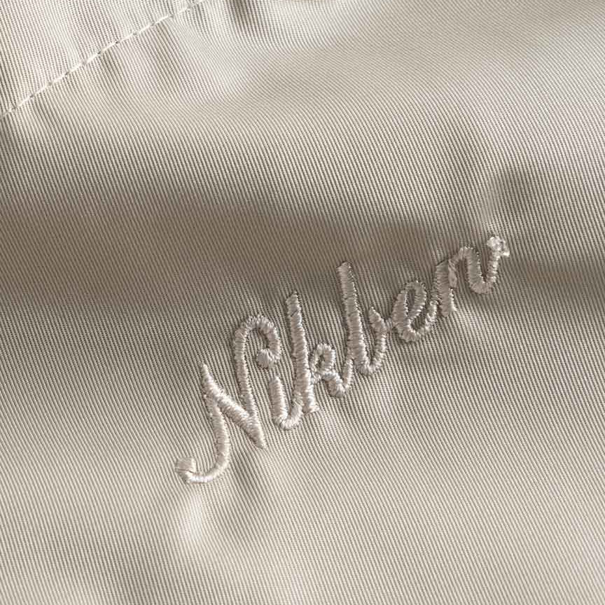 Close up on embroidered logo on a pair of beige polyester shorts