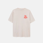 Cream colored t-shirt with red logo on chest.