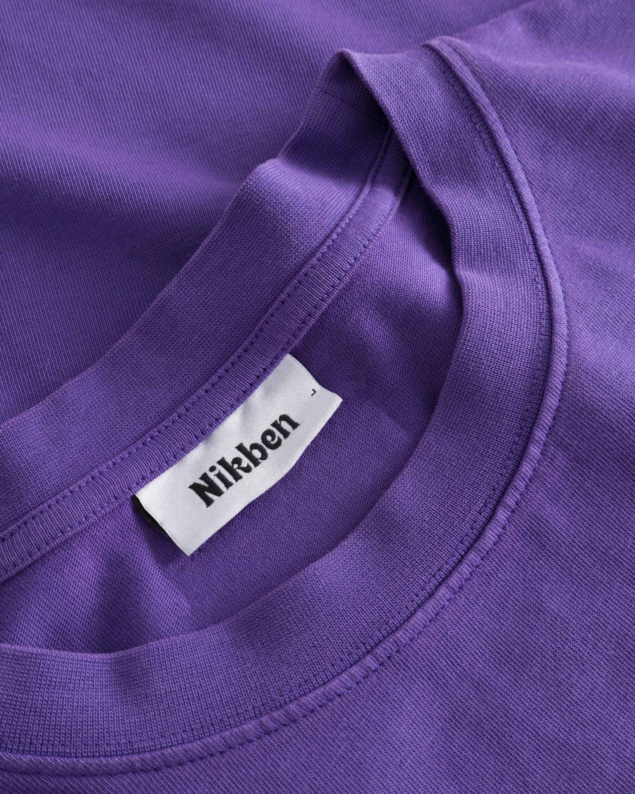 Close-up of round neck and stitching on purple T-shirt