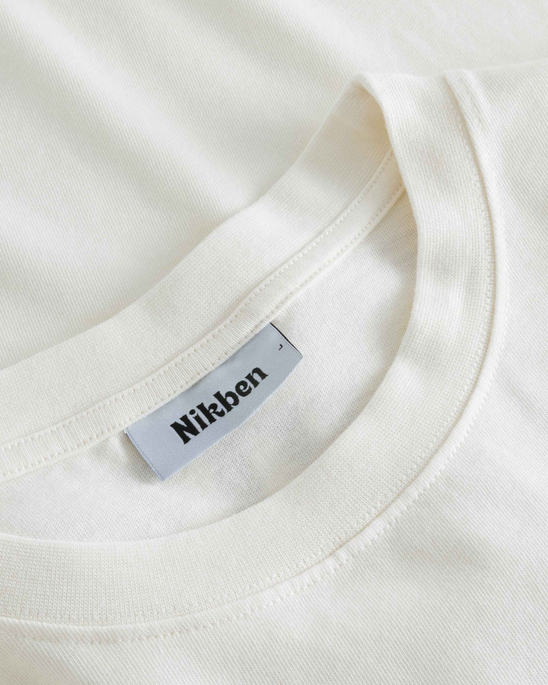 Close-up view of the round neck and stitchings on an off white t-shirt