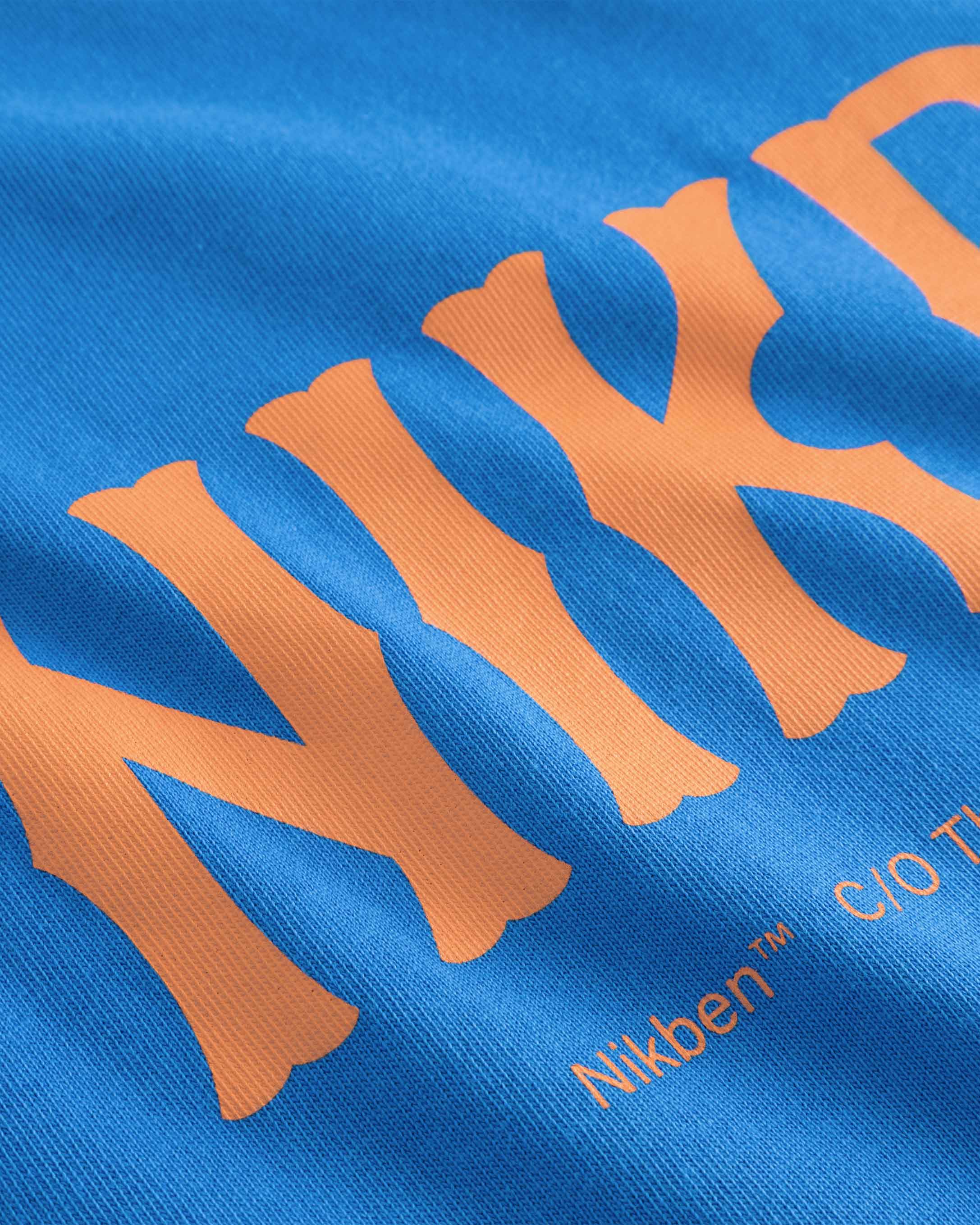 Close up of orange text print on a blue t-shirt.