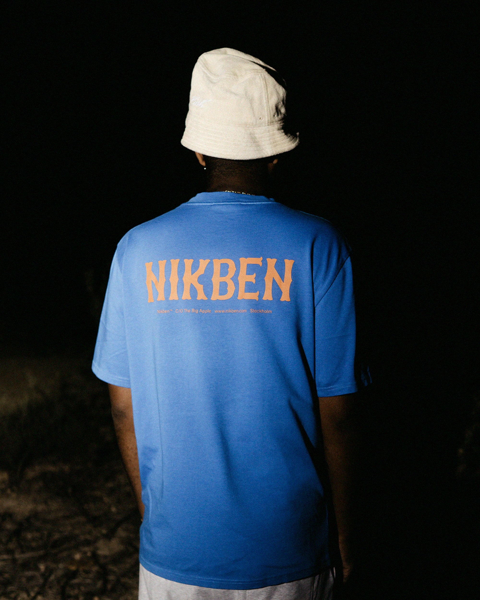 Back view of male model wearing a blue t-shirt with orange 