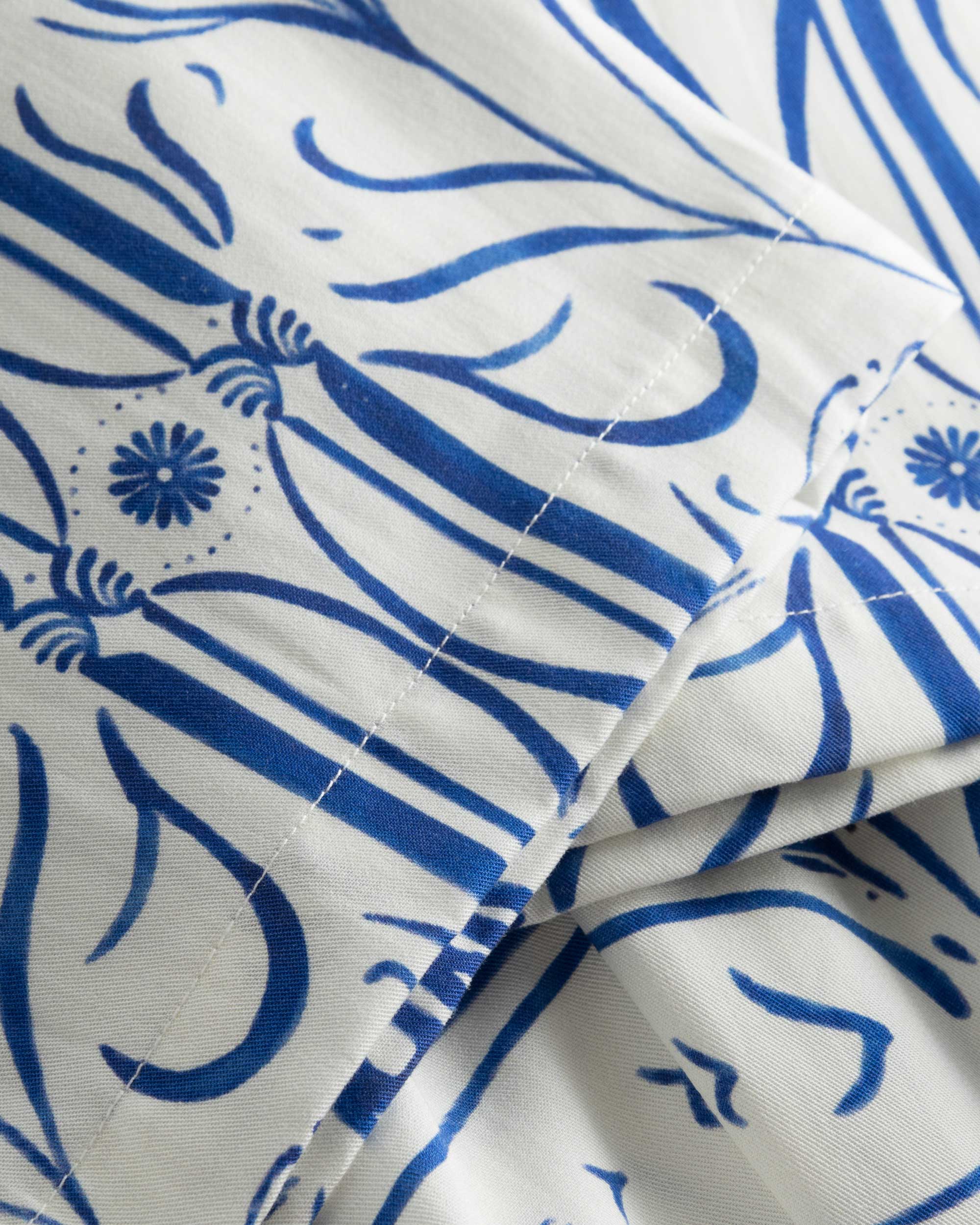 Close-up of stitchings and blue graphic pattern on white vacation pants 