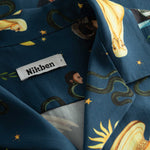 Close-up of the open collar and multi-colored graphic pattern on a navy vacation shirt.