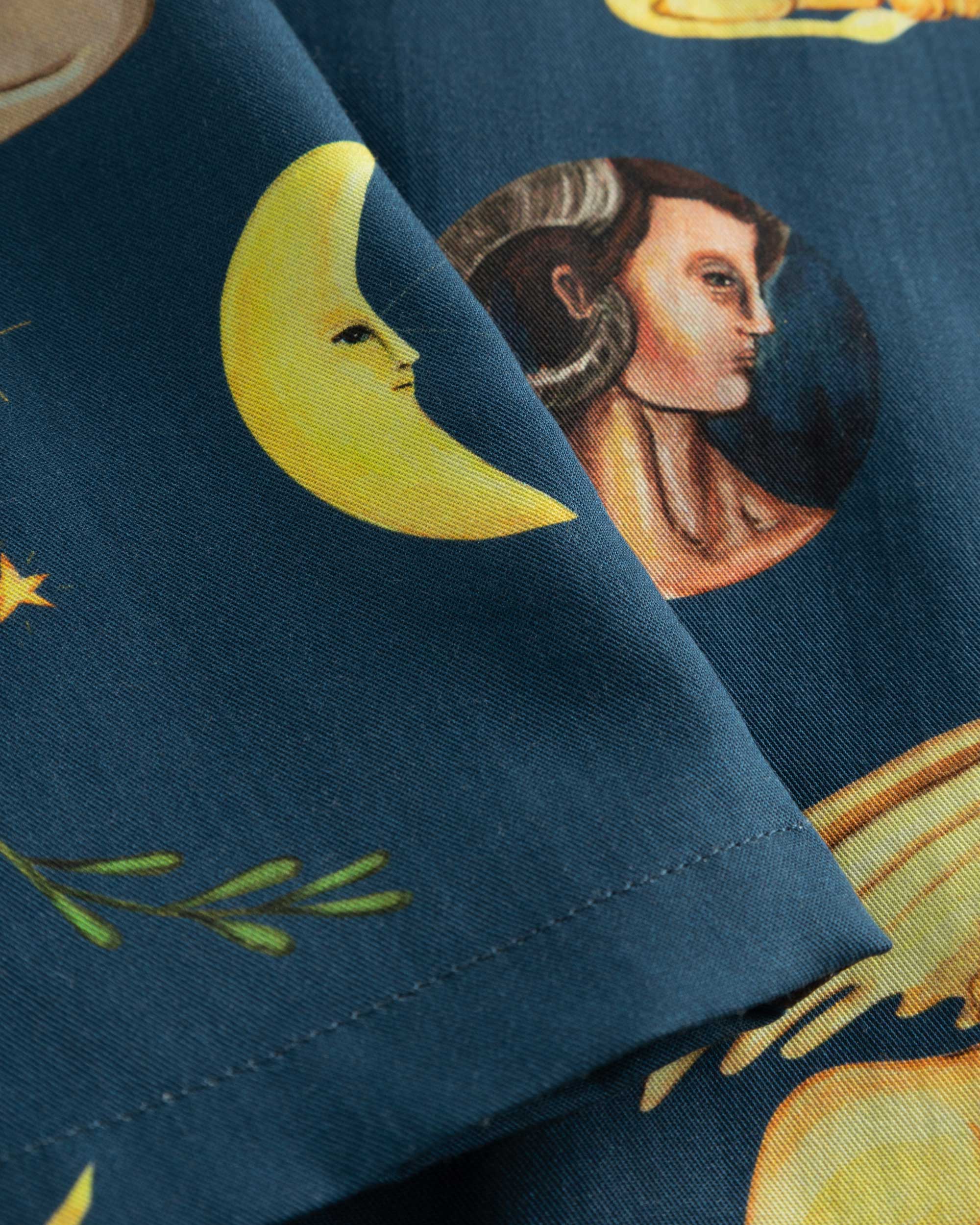 Close-up of stitchings and multi-colored graphic pattern on a navy vacation shirt.