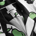 Close-up on open collar on a black and white short-sleeved vacation shirt with green pear illustrations.