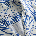 Close-up of the open collar on a white short-sleeved vacation shirt with blue graphic pattern