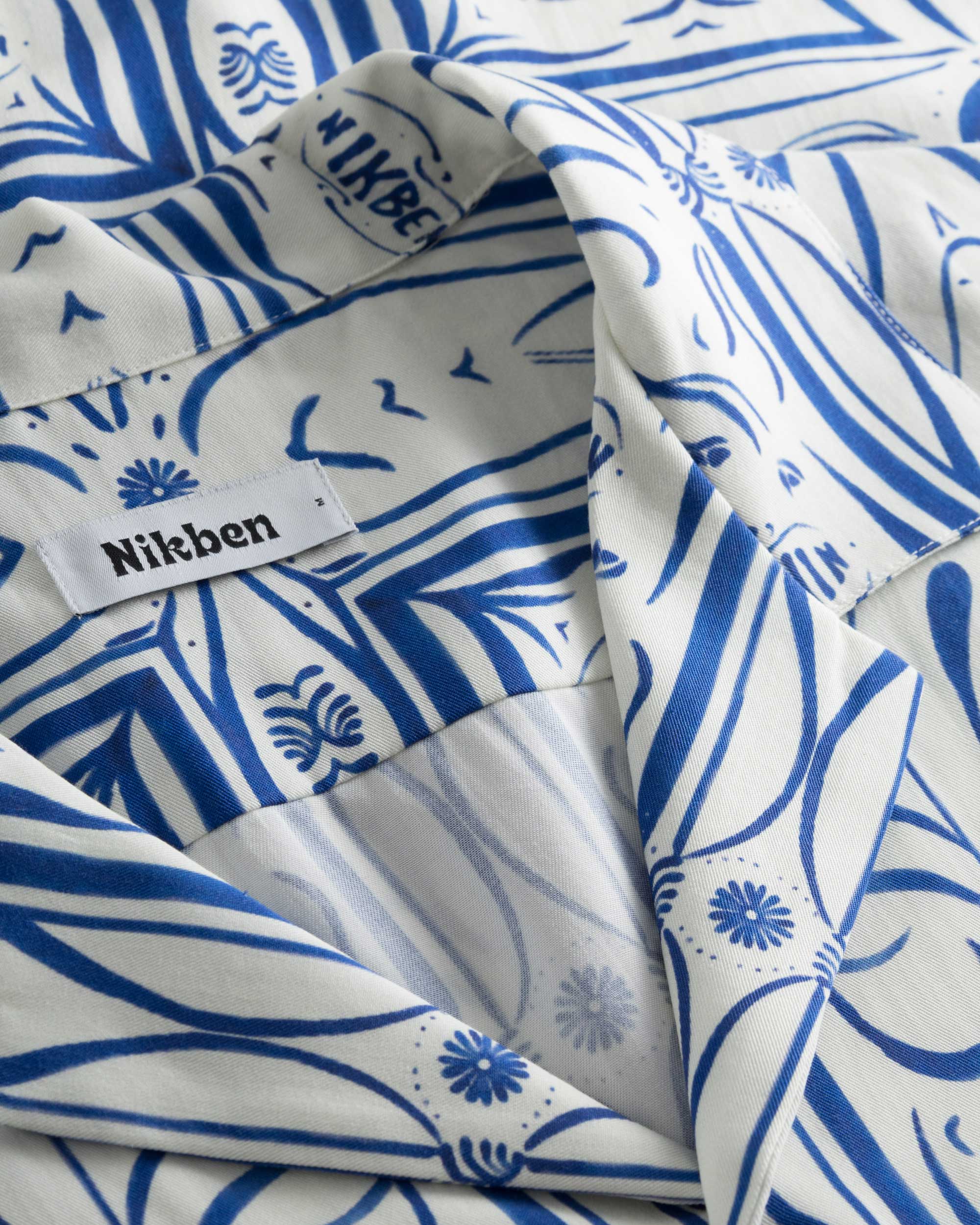 Close-up of the open collar on a white short-sleeved vacation shirt with blue graphic pattern