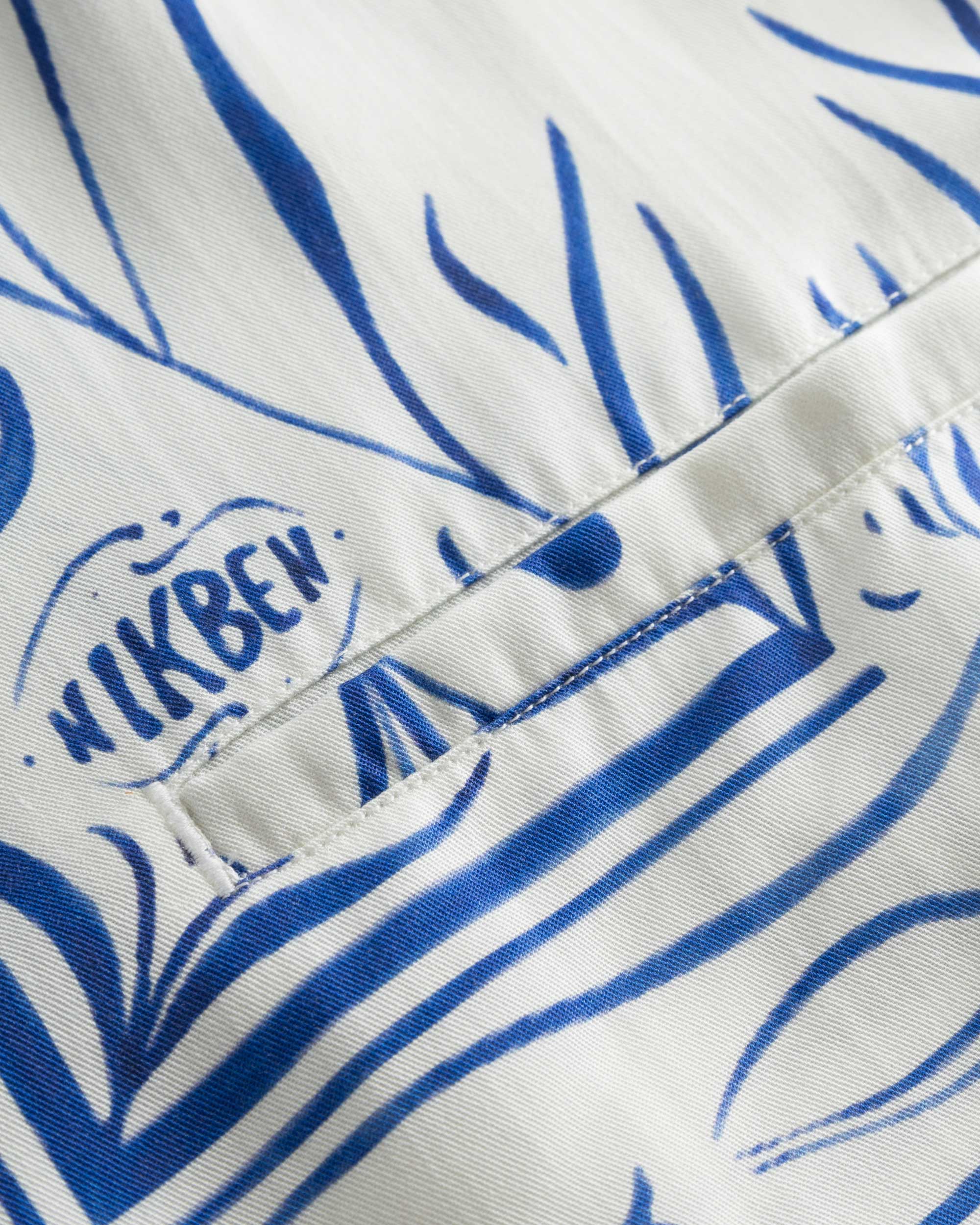 Close-up of the breast pocket on a white short-sleeved vacation shirt with blue graphic pattern