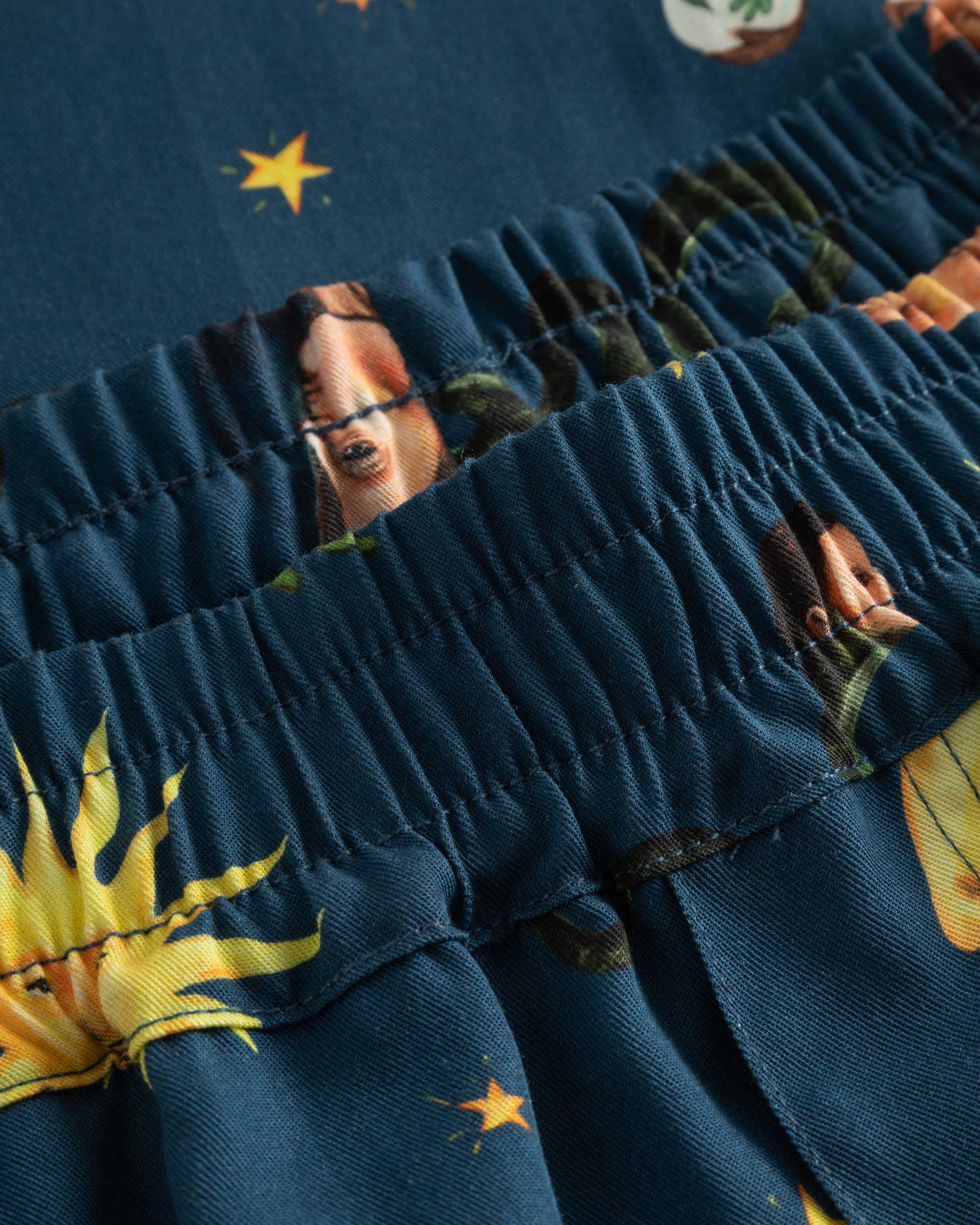 Close-up of elastic waistband and stitchings on navy vacation shorts with a multi-colored graphic pattern.