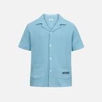 Sky blue waffle-patterned short-sleeved shirt with two front pockets, featuring a stitched black Nikben logo on the left pocket and button closure.