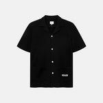 Black waffle-patterned short-sleeved shirt with two front pockets, featuring a stitched black Nikben logo on the left pocket and button closure.