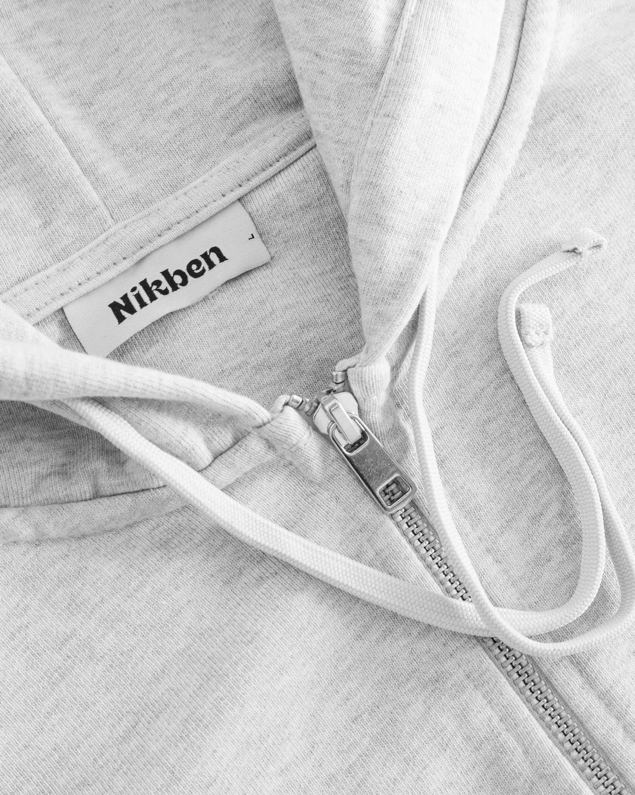Close up view of zipper and drawstrings on grey hoodie.